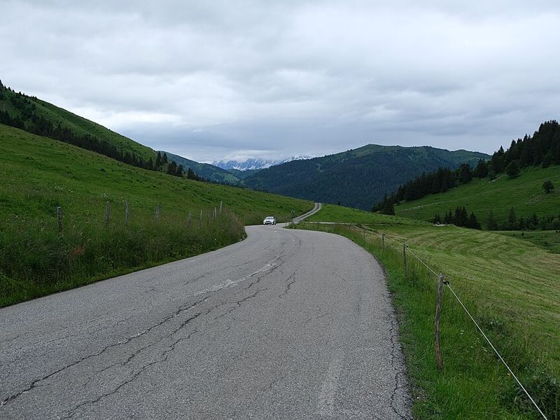 Winding road through Alpine meadows at Col des Aravis